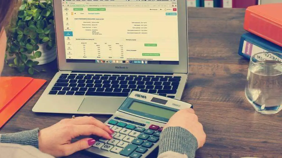 mujer frente a una computadora y calculadora